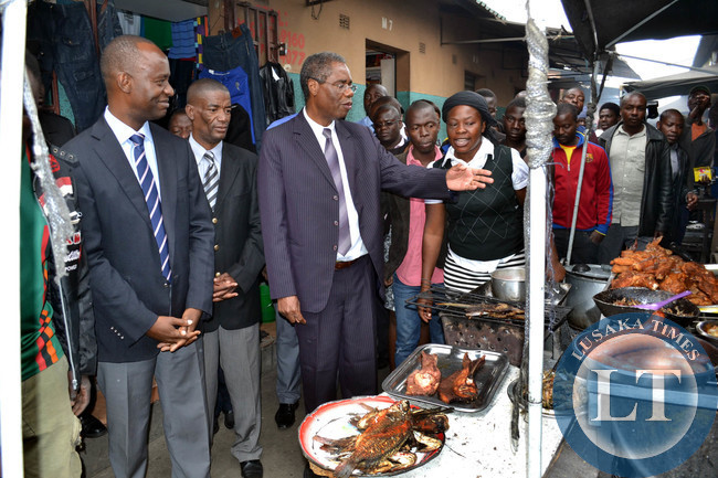 Local Government Minister Emmanuel Chenda talks to traders at Lusaka town centre market as Lusaka Mayor Mulenga Sata (left) looks on