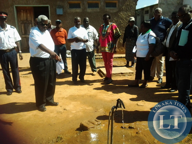 Deputy secretary to cabinet Ambassador Peter Kasanda pointing at a broken down tap whose water was running at youth skills resource Centre in Mumbwa