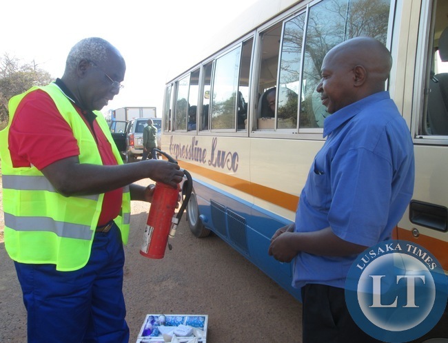 captions Communications and Transport Deputy Minister Panji Kaunda yesterday mounted a Road Block at Prospect police Camp near Kabwe where he Impouded a number of Vehicles which had faults .In the picture, Mr Kaunda inspects the fire Extinguisher from a Rosa Bus while the Driver of a Bus looks on