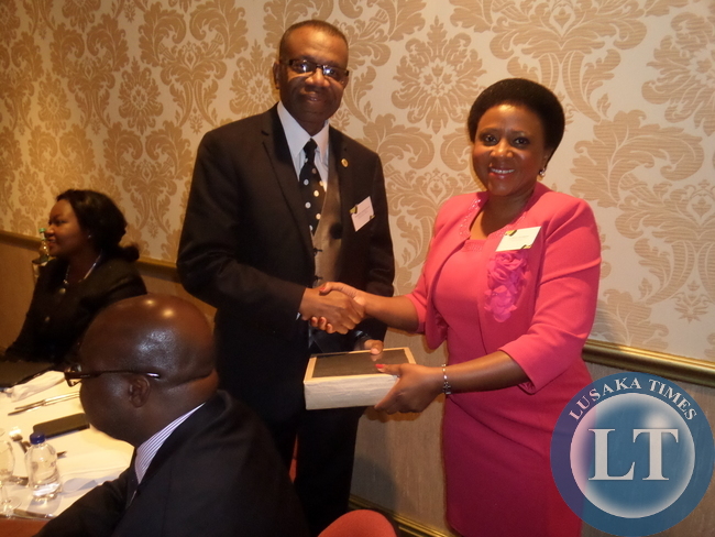 AFRICAPACITI Group Chairperson, Dr. Millicent Mombeshora (right) presents a sample of the building material to be used in the housing project to Zambia's High Commissioner to South Africa, Mr. Muyeba Chikonde