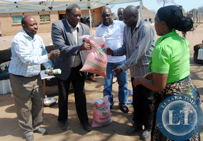 PANNAR Seed limited Southern regional manager Ernest Chikote (far left), Chief Chikanta (in jacket) with Kalomo District Agricultural Coordinator Max Choombe hand over a 10 kgs bag of pannar seed to Kenmax Hamoonga and his wife, Angela after losing 5,000 by 50 kg bags destroyed by fire recently at his farm in Chief Chikanta’s area in Kalomo