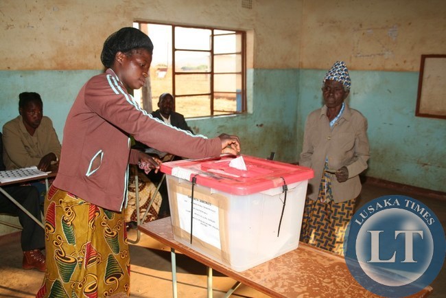 JOYCE Daka, casts a vote on behalf of her visually impaired grandmother, Tiwamyenji Miti ( right) cast her vote at Mtaya Basic school polling station in a Kasenengwa parliamentary by-election in Chipata