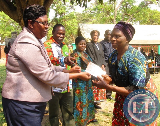 CENTRAL Province permanent secretary Edwidge Mutale handing over a Cheque worth K2, 000 to Highridge ward women's club chairperson Idah Chishinga during the cheque presentation ceremony to seven clubs