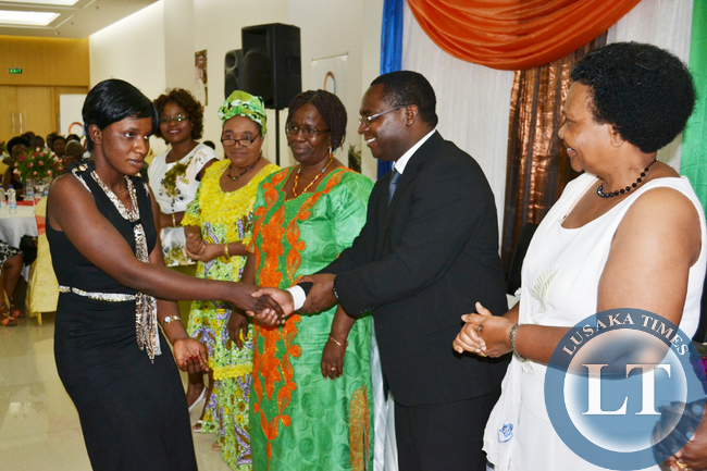 ambia Breweries Corporate Affairs Director Luke Njovu (second from right) shakes hands with Mongu rice grower Chuma Mulimukwa for scooping the Rural Woman Entrepreneur of the Year award (left) as Zambia Federation of Associations of Women in Business Chairperson Nancy Kawandami (right) looks on at the Month of the Woman Entrepreneur awards dinner at Government complex in Lusaka recently.