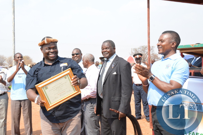 Chief Madzimawe of the Ngoni People showing a certificate of declaration of 169 villages in his chiefdom as Open Defecation Free(ODF) as Local Government Deputy Minister John Kufuna looks on