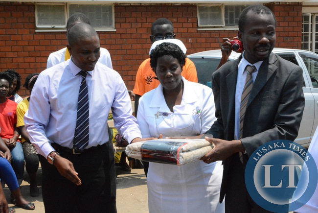 -Acting Agency Director Children International Zambia Sven Mugamya handing over the beddings to Kanyama Clinic Sister-in-charge Mubiana Kachindo (c) and Lusaka District Medical Officer Dr. Masumba Masaninga