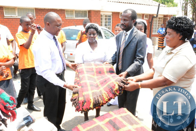 -Acting Agency Director Children International Zambia Sven Mugamya handing over the beddings to Kanyama Clinic Sister-in-charge Mubiana Kachindo (c) and Lusaka District Medical Officer Dr. Masumba Masaninga