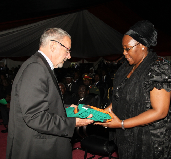Acting President Dr. Guy Scott presenting the national flag to first lady Dr. Christine Kaseba Sata during the burial