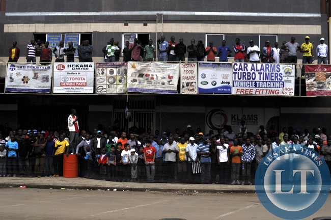 Spectators watching rally cars from roof tops and along shop corridors