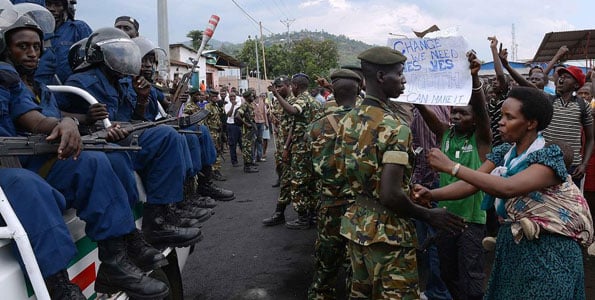 Burundian soldiers control protesters facing riot police seated in a pickup truck in Musaga, on the outskirts of Bujumbura, on April 29, 2015, during demonstrations against the President's bid for a third term. Since the protests started, the army has regularly come between the police and demonstrators to avoid further clashes and the protesters believe the soldiers are neutral. AFP PHOTO | SIMON MAINA