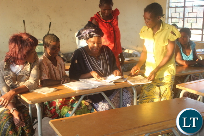 Ms. Nawakwi checks some books of grade 4 adult pupils at Milulu Primary School.