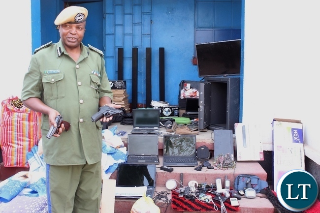 Western Province Police Commissioner Charles Lungu displays a real pistol (l) and a toy one (r) during a stolen property identification display at Mongu Central Police yesterday, recovered from suspected criminals during an operation conducted over the weekend in Limulunga and Mongu Districts. Three suspects are in custody while two are on the run.
