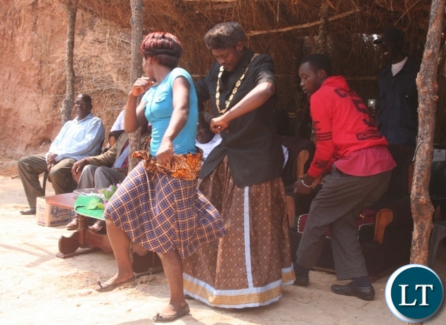Acting Solwezi mayor Brian Kajoba (r ) joins Nsomo cultural group dancer Felistus Malingosa in dancing beauty is made and fined song during the Kuvuluka Kishakulu tradition ceremony at chief Matebo’s grounds in Solwezi on Saturday as Acting Solwezi district commissioner Muyobo Shimabale (far left) looks on
