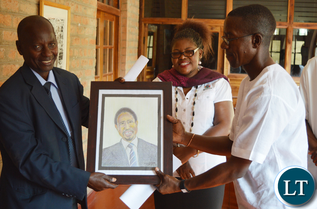 Mazabuka based artist Alec Lishandu (right) handles over an artistic portrait of President Edgar Lungu to Choma district administrative officer Vincent Sikanyela while Choma Museum director Bevine Sangulube looks on during opening of an art exhibition at the museum