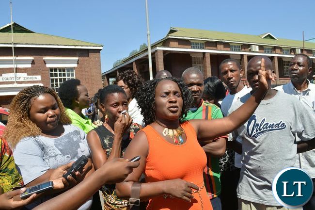 Former Livingstone Mayor Aggrey Njekwa's young sister, Suzanne (middle), prays for the jailed brother outside the Livingstone High Court
