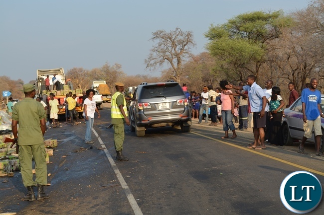 Kazungula District Commissioner Pascalina Musokotwane (in white t-shirt) and police officers trying to control residents from looting the cooking oil which dropped on the roadside after a truck overturned