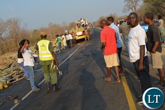 Kazungula District Commissioner Pascalina Musokotwane (in white t-shirt) and police officers trying to control residents from looting the cooking oil which dropped on the roadside after a truck overturned