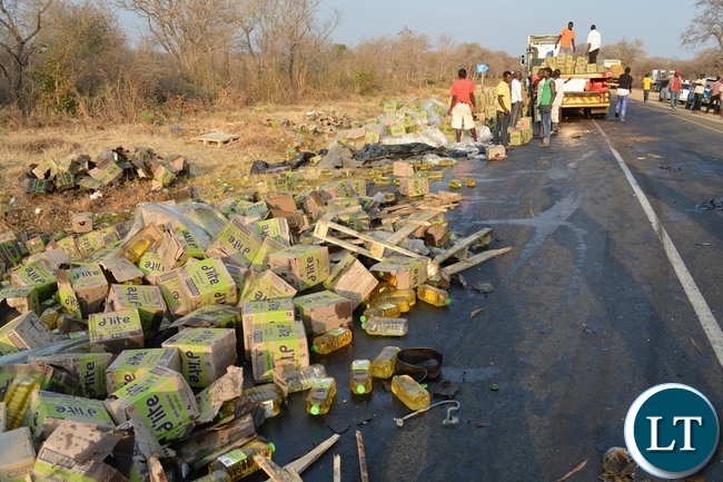 Kazungula residents helping to load into a truck cases of cooking oil which dropped on the roadside after a truck overturned