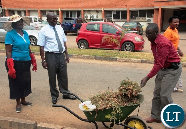 Zambia News and information Services Director Patrick Lungu load the west in the wheelbarrow whilst Ministry of Information and Broadcasting Service Permanent Secretary Godfrey Malama and his Human Resource Director Christine Mushanga (l) look on during the relaunch of KEEP ZAMBIA CLEAN at Mass media
