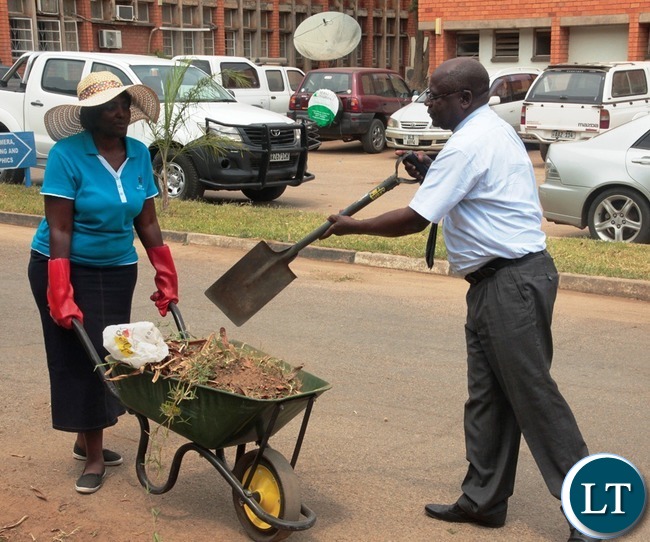 Ministry of Information and Broadcasting Service Permanent Secretary Godfrey Malama load the west in the wheelbarrow whilst his Human Resource Director Christine Mushanga is holding the wheelbarrow during the relaunch of KEEP ZAMBIA CLEAN at Mass media