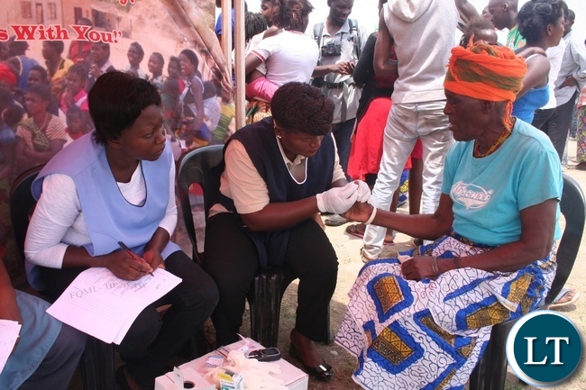 A nurse from Solwezi general hospital Cynthia Muyoya (m) checks sugar levels of a 70 year old Esnart Mashilipa (r ) of Kazomba compound during random sugar level checking to commemorate this year’s World Health Diabetes Day held at Kyawama school grounds last Saturday in Solwezi as her counterpart Bupe Sachibobe (l) looks on.