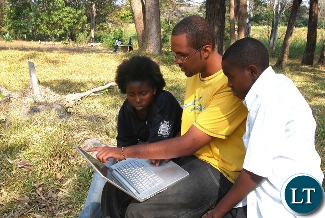 My son Sekani Tembo who was a Third year computer major in at an American College showing his cousins, Abiudi and Nina, a lap top computer behind the Castle Hotel in Lundazi in 2009