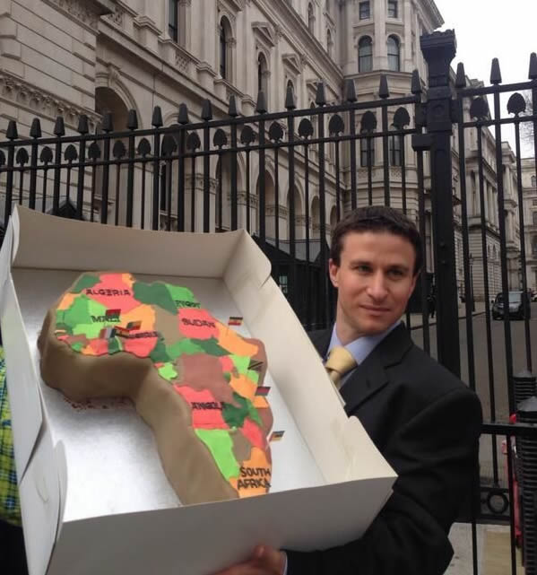 One of the campaigners outside Downing Street – where the UK Prime Minister and Chancellor live – holds up a cake of Africa with New Alliance countries marked out with flags. Photo: WDM