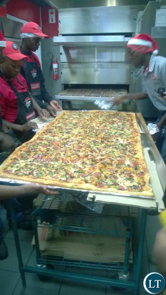 Pizza Hut workers unveiling the largest pizza ever made in Zambia