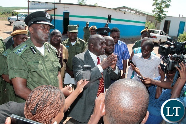 Kafue District Commissioner Ngoni Moyo (in a suit) who is flanked by Inspector General of Police Kakoma Kanganja (l) speaking to residents shortly after inspecting Mtendere Police Post in Chawama Compound Kafue that was damaged by people in the area