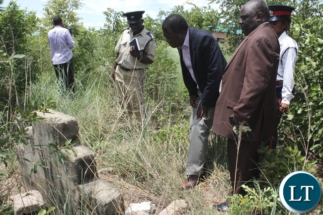 Mongu District Commissioner Susiku Kamona (c) and his Town Clerk Mwiya Mwiya (l) checking the dates on the tomb stone on a grave site yesterday which encroachers who are building houses in the old Mongu Cemetery are demolishing. Mongu District Commissioner Susiku Kamona (c) and his Town Clerk Mwiya Mwiya (l) checking the dates on the tomb stone on a grave site yesterday which encroachers who are building houses in the old Mongu Cemetery are demolishing.