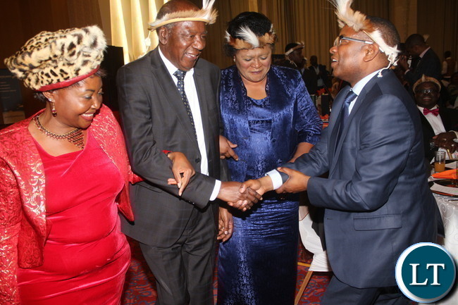 Minister Alexander Chikwanda flanked by Angela Cifire and Sherry Thole while shaking hands with ZESCO CEO Victor Mundende.