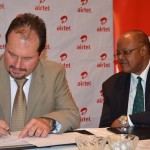 Airtel Managing Director Peter Coreil(l) signs the memorandum of understanding while Permanent secretary to the cabinet Augustine Seyuba(r) looks