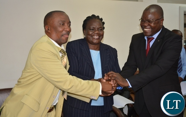 Permanent Secretary for Minister of Youth sports and child development Ms Agnes Musunga shake hands with the President of Street Vendors Association Mr Teddy Sinkala and General Manager for Zampost Best Mwaichi sings the memorandum of street vendors