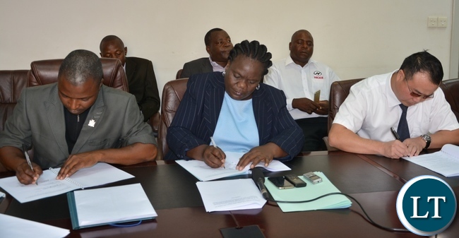 Permanent Secretary of the Ministry of Youth Sport and Child Development Ms Agnes M Musunga sings the memorandum of implementation of the empowerment scheme for the youth bus drivers with Mr Majuru Secretary General of the Public and private bus drivers Associations of Zambia and General of the Public and private bus drivers Associations of Zambia Wu Ming
