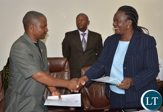 permanent Secretary of the Ministry of Youth Sport and Child Development Ms Agnes M Musunga shake hands with General of the Public and private bus drivers Associations of Zambia Wu Ming during the singing ceremony of the memorandum of implementation of the empowerment scheme for the youth bus drivers with Secretary