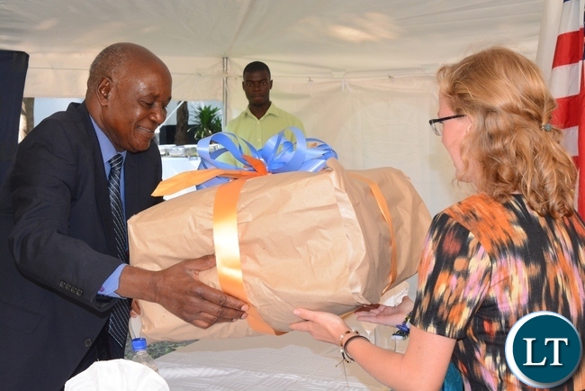 Busoli royal establishment Principal adviser John Luputa(l) being presented with a gift by one of the peace corps volunteers Kelsi Grogan(r) during the swearing in ceremony for rural aquaculture promotion and linking income,food and environment project volunteers