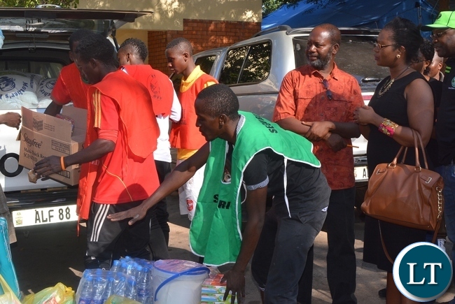 The President for law Association of Zambia Ms Linda Kasonde (r),donates foods staff to the refugees at st Ignatius Catholic church in Lusaka while Father Charles Chilinda looks (L)