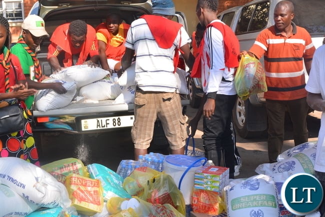 The President for law Association of Zambia Ms Linda Kasonde (r),donates foods staff to the refugees at st Ignatius Catholic church in Lusaka while Father Charles Chilinda looks (L)