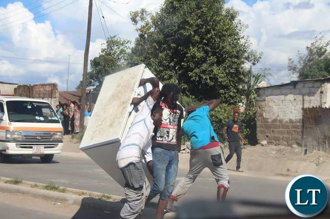 Some guys carrying a fridge believed to be looted along Zingalume - Matero road.