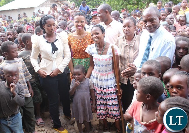 Ubulayo Charity organization founder Tasila Lungu with Hildah Nkole 7, a pupil at Chiba Community School in Kasama district today after she made a donation of shoes to over 200 vulnerable and orphaned pupils at the school. Looking on is Kasama District Commissioner Kelly Kashiwa and School Head Catherine Bwalya (walking stick)