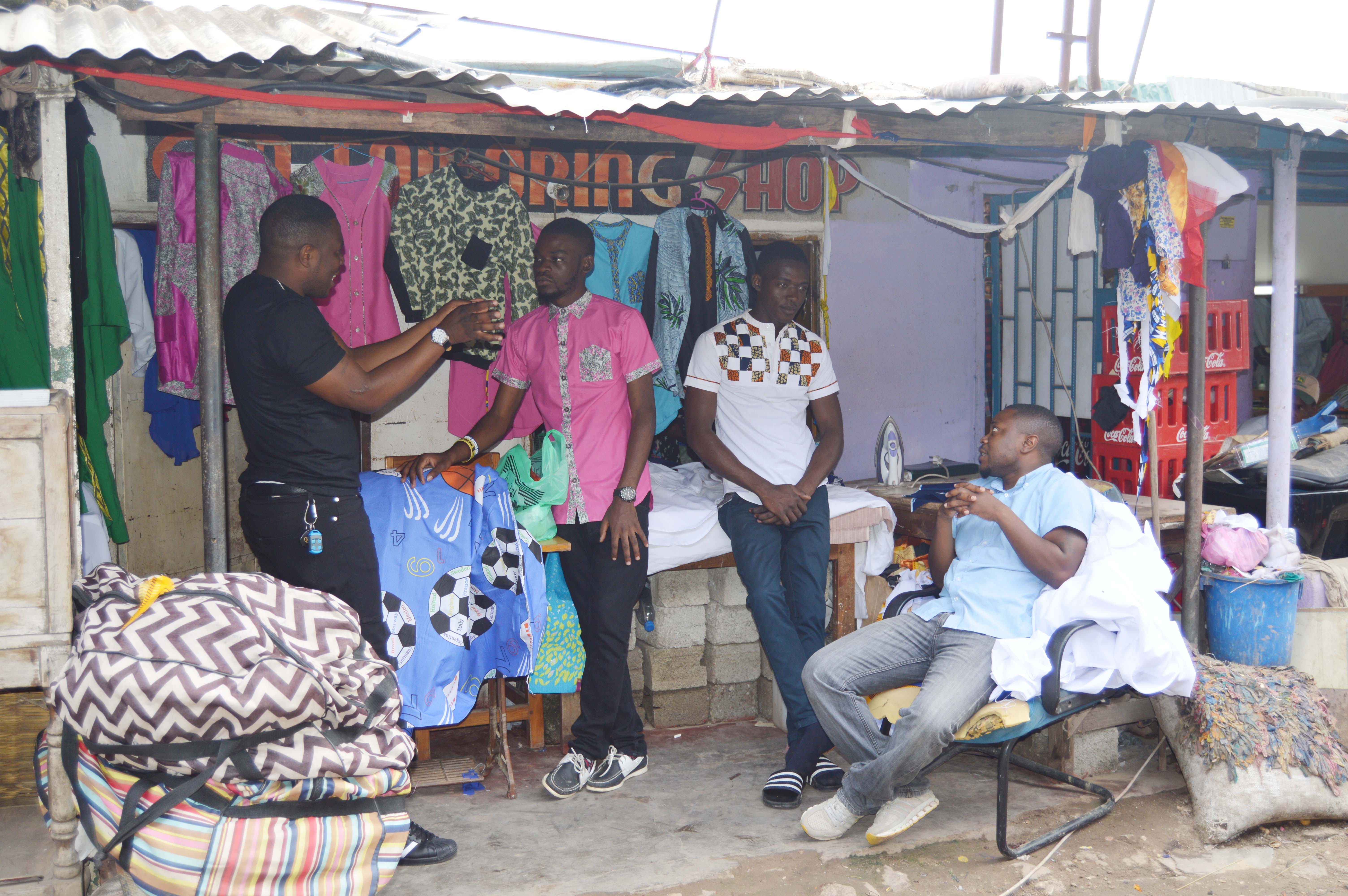 Designer and Tailors Timothy Mwandila and Mark Mafuleka chatting with custimers at their shop at Normead Market in Lusaka, Zambia. Picture by Hope Mkunte