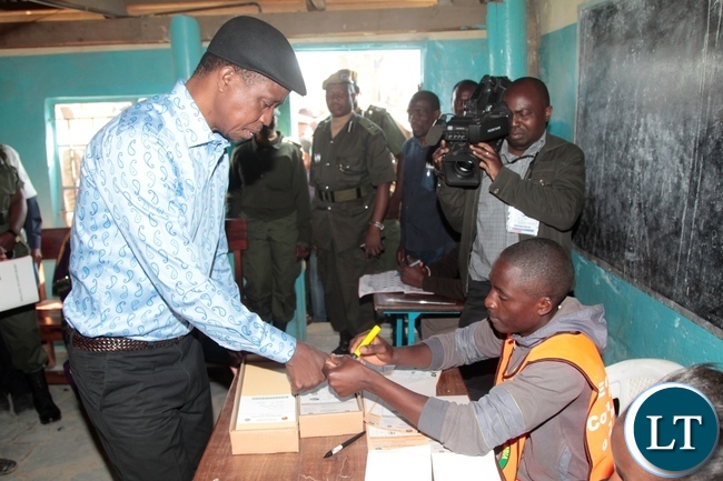 President Edgar Lungu receive the ballot paper from polling assistant shortly before casting his vote in Chawama Constituency at Apostolic Faith Church