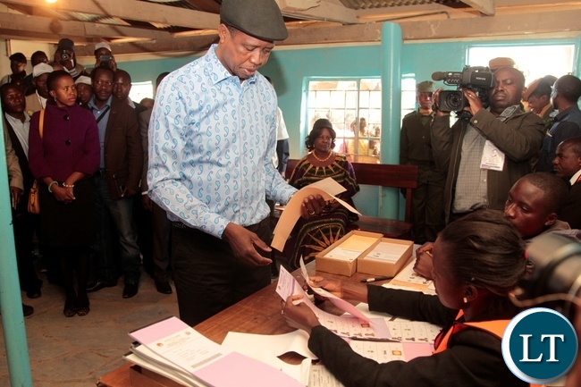 President Edgar Lungu receive the ballot paper from polling assistant shortly before casting his vote in Chawama Constituency at Apostolic Faith Church