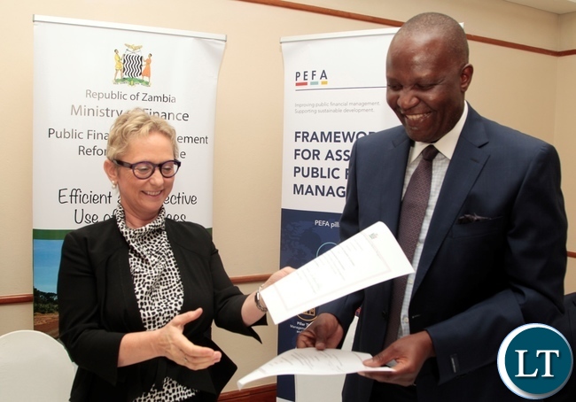 Minister of Finance Felix Mutate and World Bank Country Manager Ina-Marlene Ruthenberg exchange the documents after signing ceremony of the first amendment to the grant agreement of the Public Financial Management Reform and launch of the Zambia PEFA assessment 2016