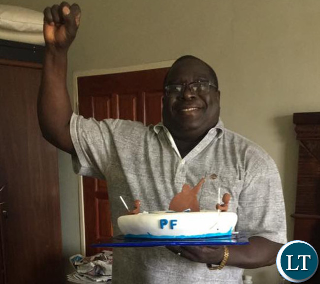 Kambwili displays his birthday cake whilst raising a fist, a PF symbol