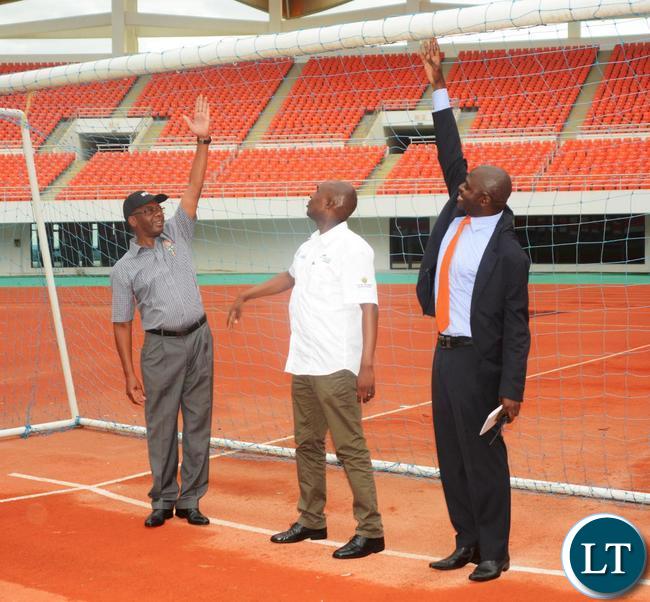 Minister of Works and Supply Mathew Nkhuwa(r),Lusaka Province Minister Japhen Mwakalombe(c) and Ministry of Housing and Infrastructure Development Structural Engineer Francis Mundanya(l) trying the goal post during the tour of Infrastructure at Heroes Stadium