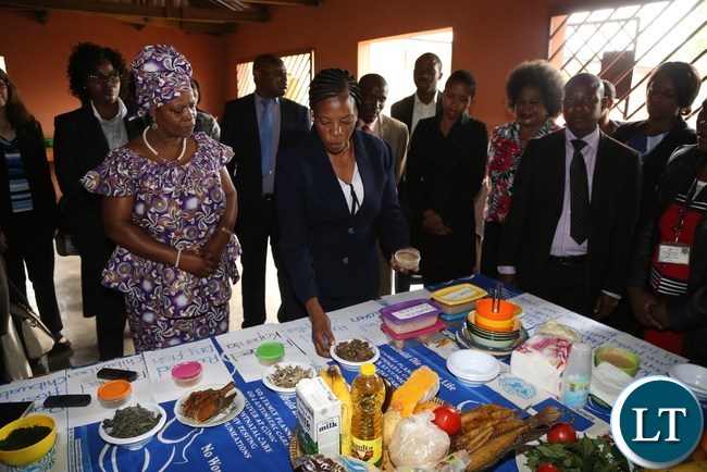 First Lady Esther Lungu flanked by Misissi Outreach Health Centre Nutritionist Lina Sianzele(r) tours some stands during the hand over of food hampers to beneficiaries of Misissi Health Outreach Center at St.Lawrence Parish in Kamwala South.