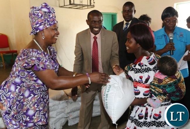 First Lady Esther Lungu presents food stuffs to Mrs Catherine Simwanza during the hand over of food hampers to beneficiaries of Misissi Health Outreach Center at St.Lawrence Parish in Kamwala South.