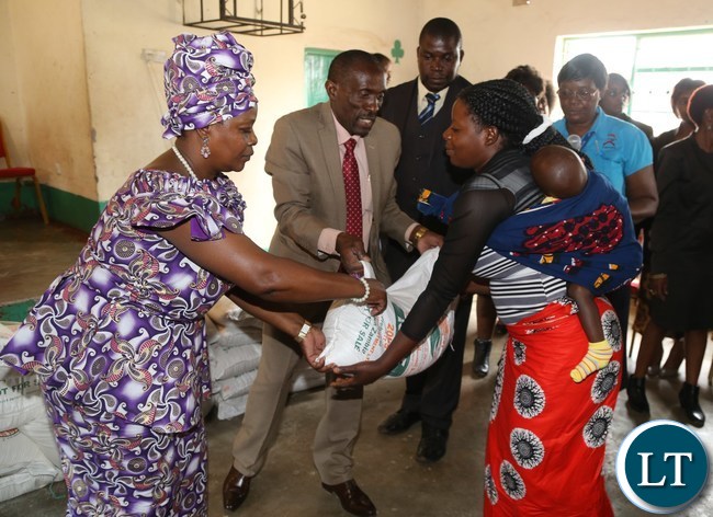 First Lady Esther Lungu presents food stuffs to Mrs Agness Langa during the hand over of food hampers to beneficiaries of Misissi Health Outreach Center at St.Lawrence Parish in Kamwala South.