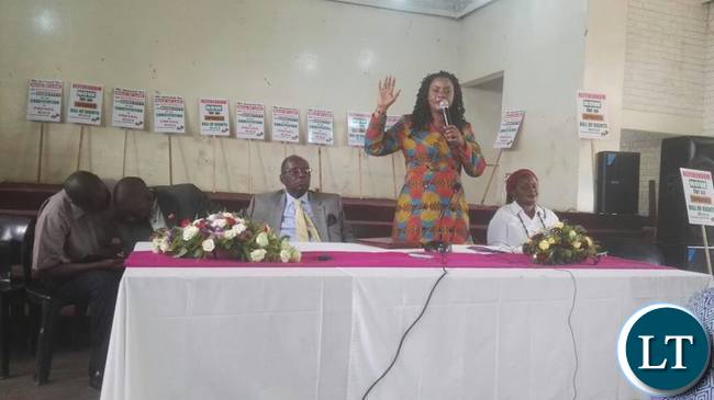 Pamela Chisanga speaks during the launch whilst Bishop Mambo and Judith Mulenga look on